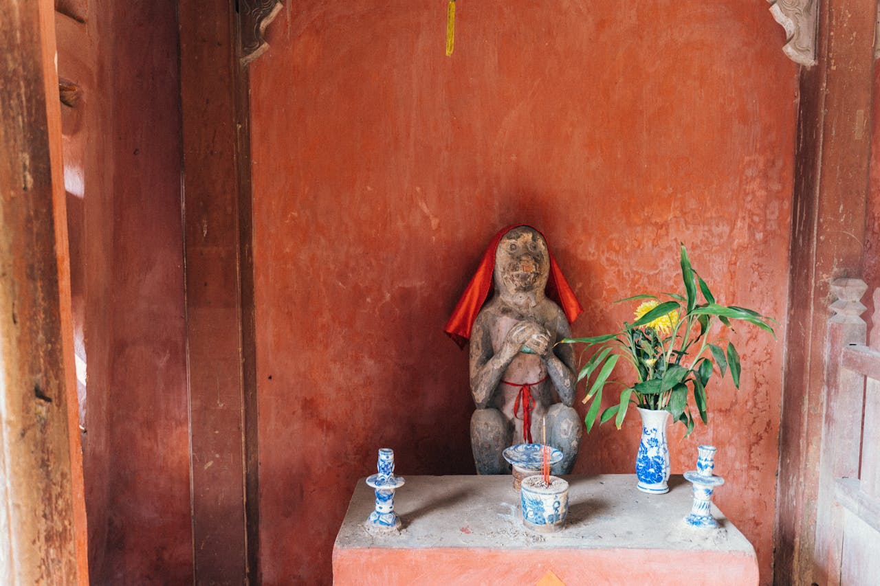 Traditional shrine in Vietnam featuring a monkey statue and offerings.